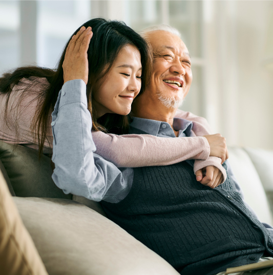 A daughter hugs her joyful father from behind