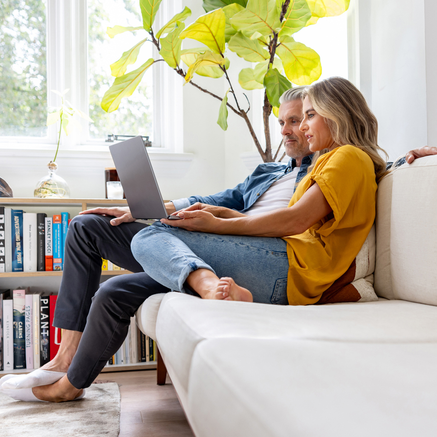 Couple on couch reading about fraud trends on a laptop