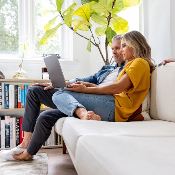 Couple on couch reading about fraud trends on a laptop