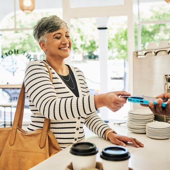 Patelco member inside at a table using her debit card and accelerating her savings using RoundUp
