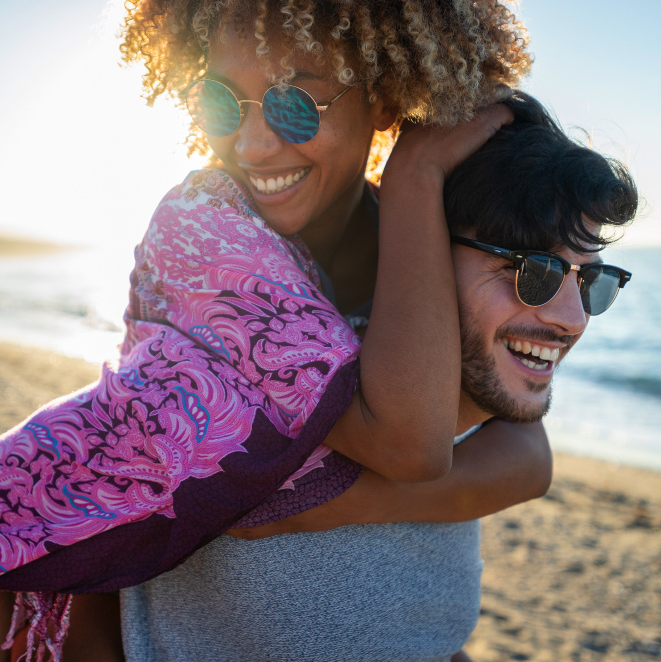 Two Patelco members goofing off together on a sunny beach